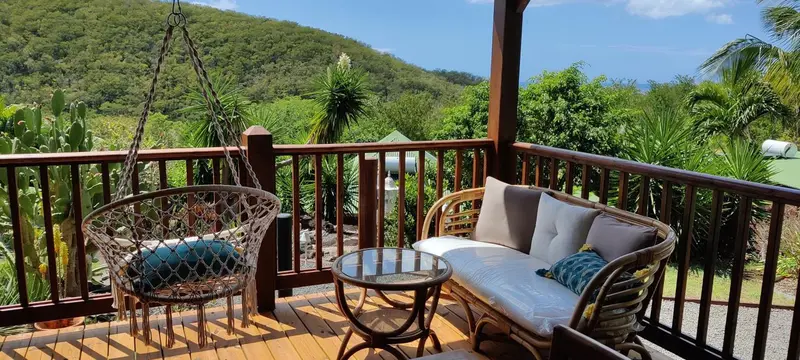 Terrasse en bois avec mobilier d'extérieur et vue sur une végétation luxuriante.