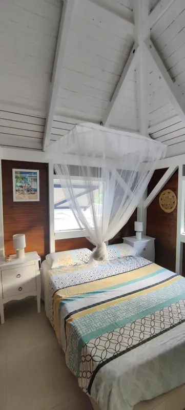 Une chambre lumineuse avec un lit à baldaquin et une décoration tropicale.