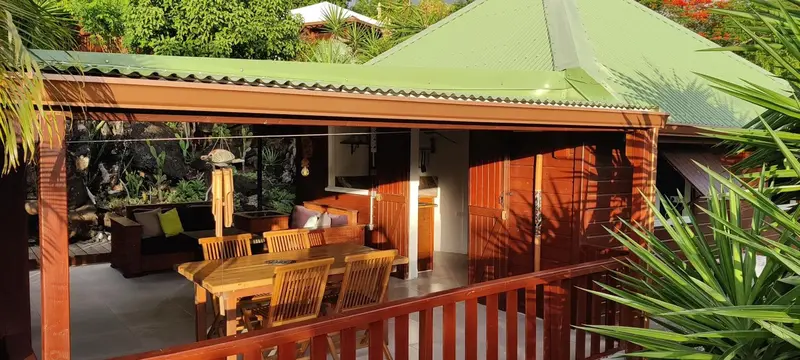 Terrasse ombragée avec mobilier de jardin et espace repas en bois.