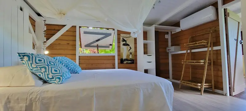 Lit recouvert de draps blancs dans une chambre au mur en bois.