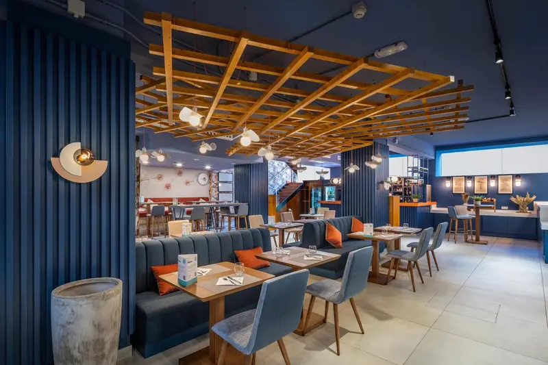 Une salle de restaurant lumineuse avec des tables et des banquettes confortables.