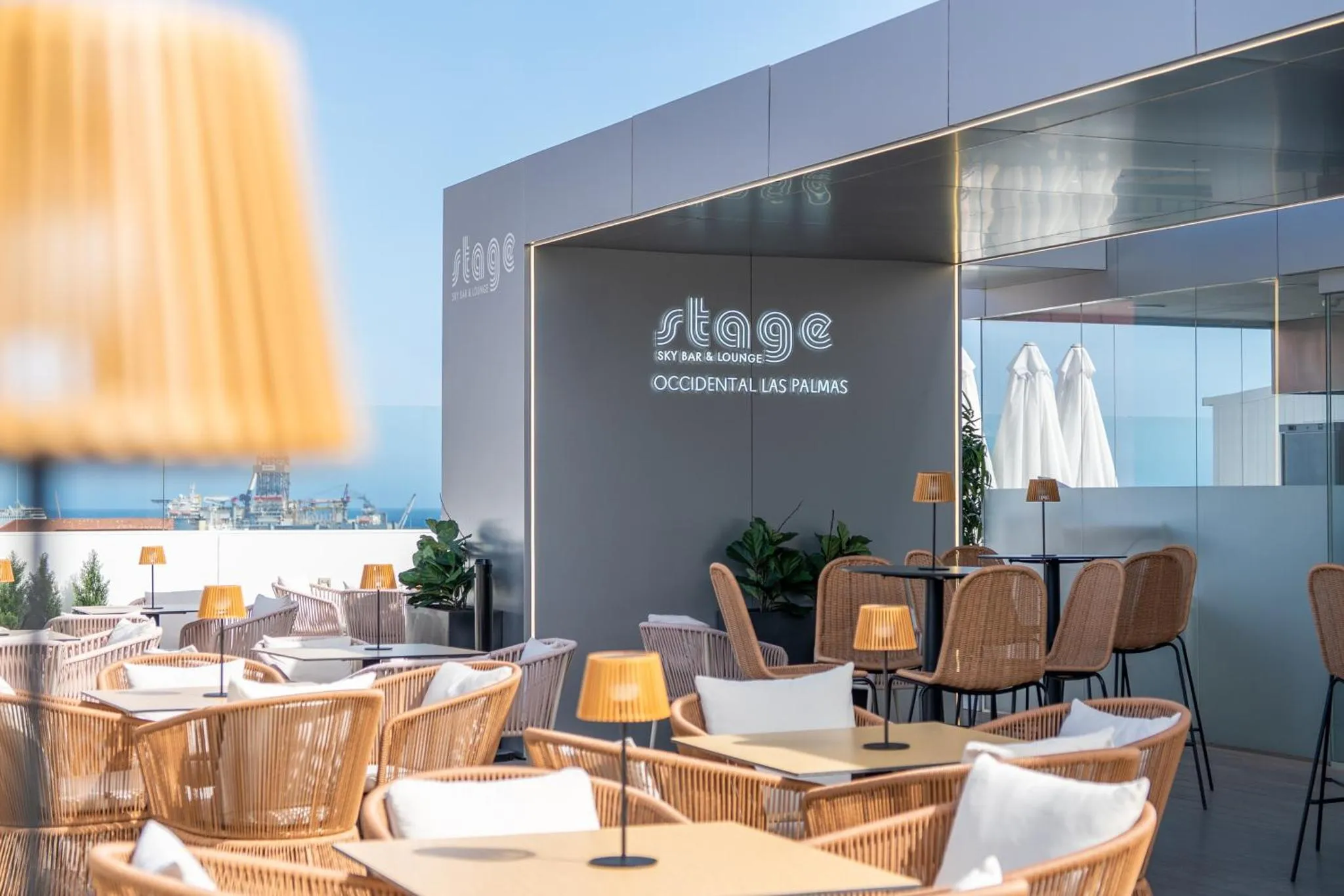 Terrasse aménagée avec tables et chaises en osier sous des parasols.