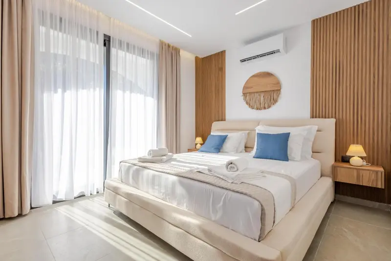 Une chambre lumineuse avec un grand lit et des rideaux beiges.