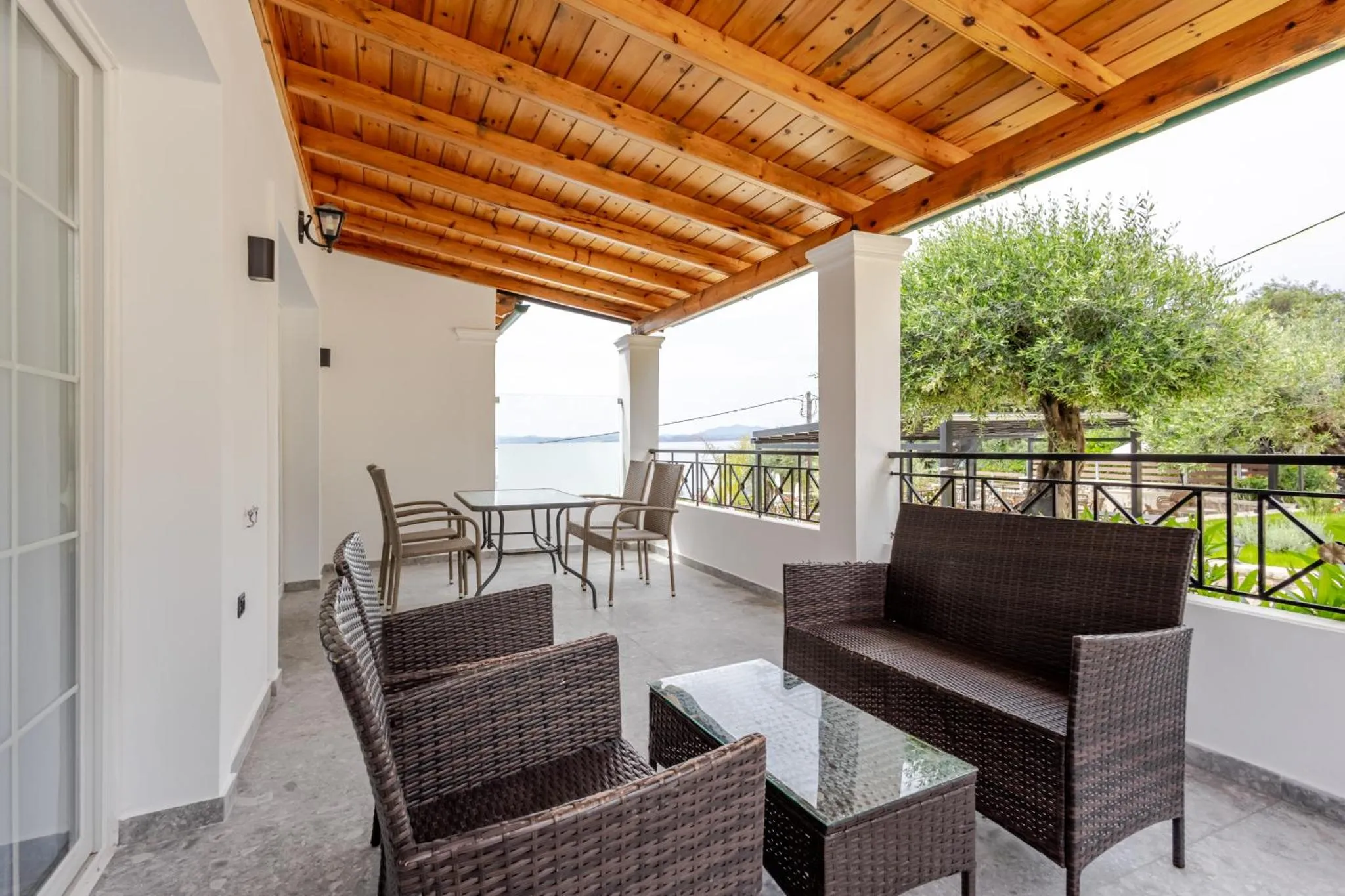Terrasse ombragée avec mobilier en rotin et vue sur la mer.