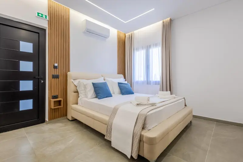 Une chambre lumineuse avec un grand lit et des oreillers décoratifs.