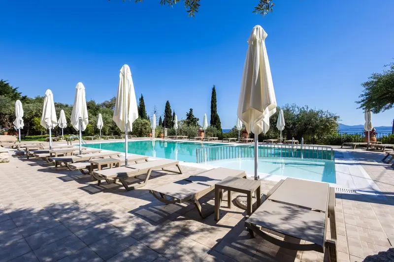 Transats et parasols bordent une piscine rectangulaire en extérieur.