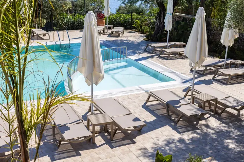Transats et parasols bordent une piscine rectangulaire ensoleillée.