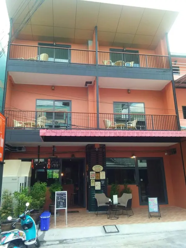 Façade d'un bâtiment orange à deux étages avec des balcons et une entrée ombragée.