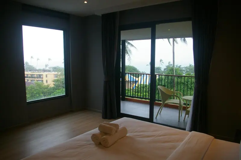 Une chambre lumineuse s'ouvre sur une terrasse avec vue sur la végétation.