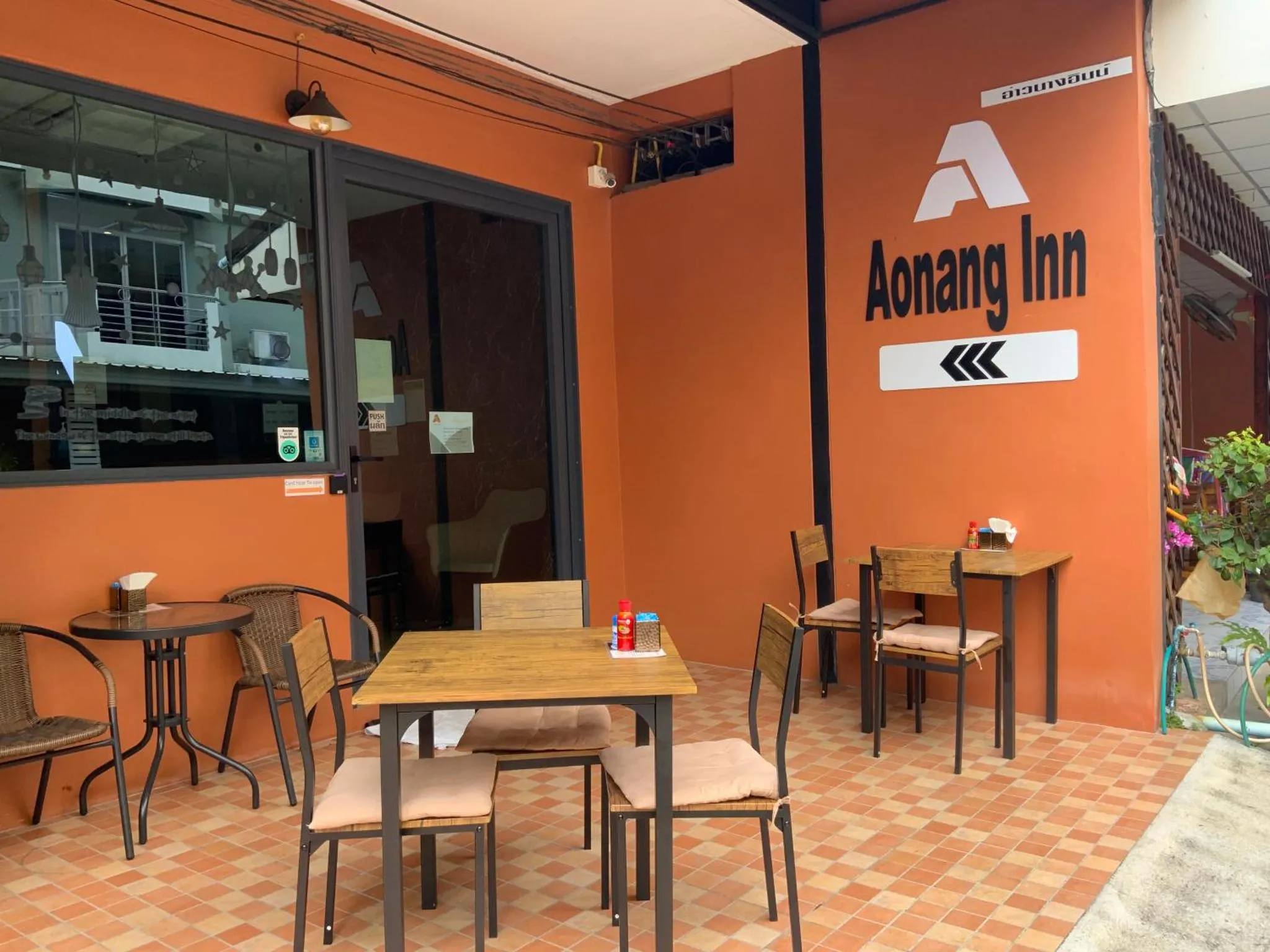Terrasse avec tables et chaises devant une entrée.