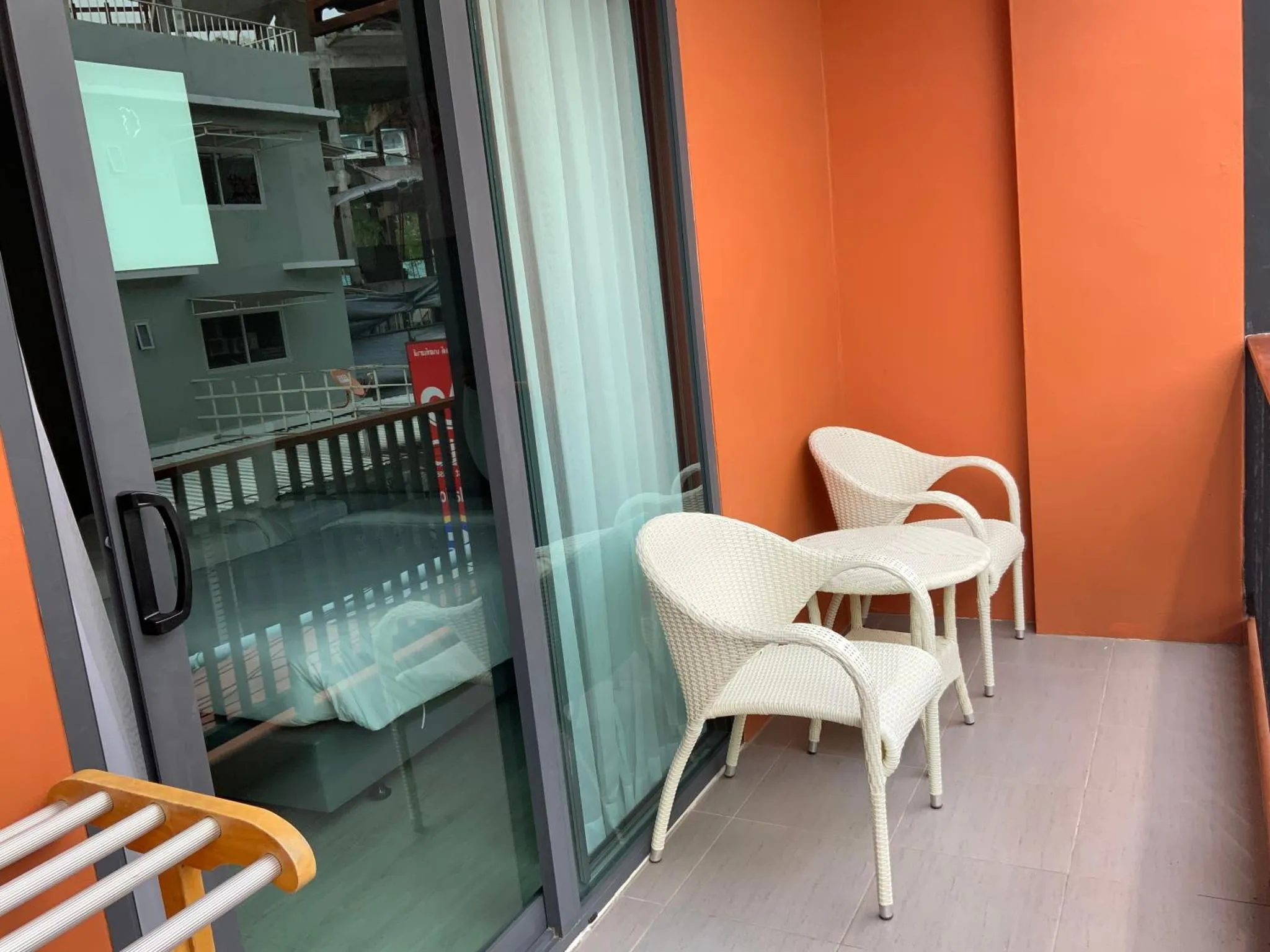 Terrasse avec mobilier en osier devant une baie vitrée.