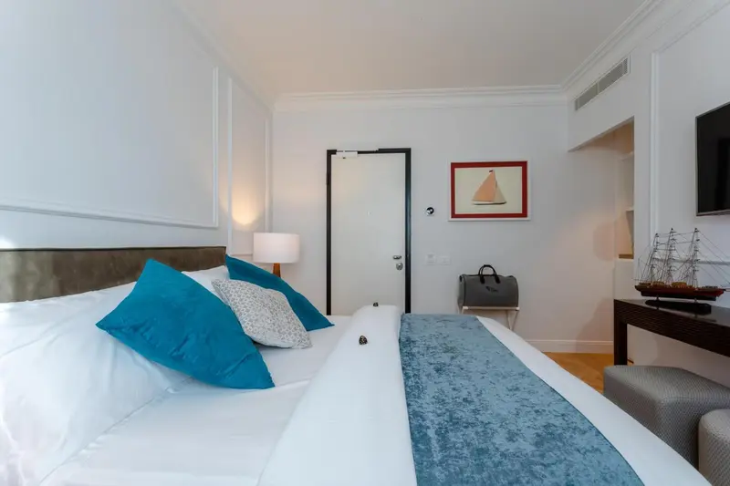 Une chambre lumineuse avec un grand lit recouvert d'une courtepointe bleue et de coussins.