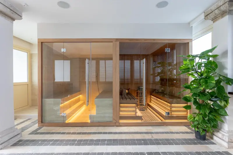 Espace sauna lumineux avec bancs en bois et plantes vertes.