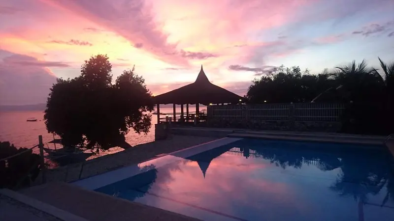 Une piscine reflète les couleurs d'un coucher de soleil sur l'océan.