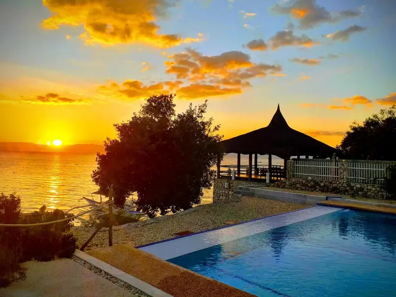 Coucher de soleil sur l'océan avec une piscine et un pavillon.