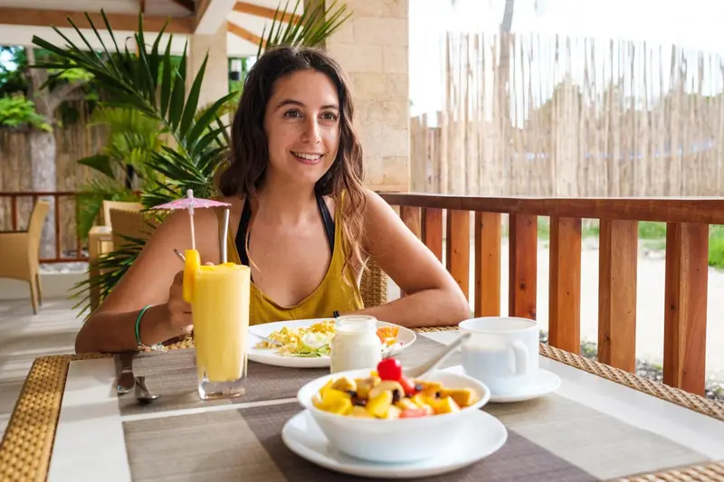 Une femme souriante est assise à une table avec un petit-déjeuner.