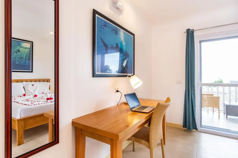 Une chambre lumineuse avec un bureau en bois et un lit décoré de fleurs.