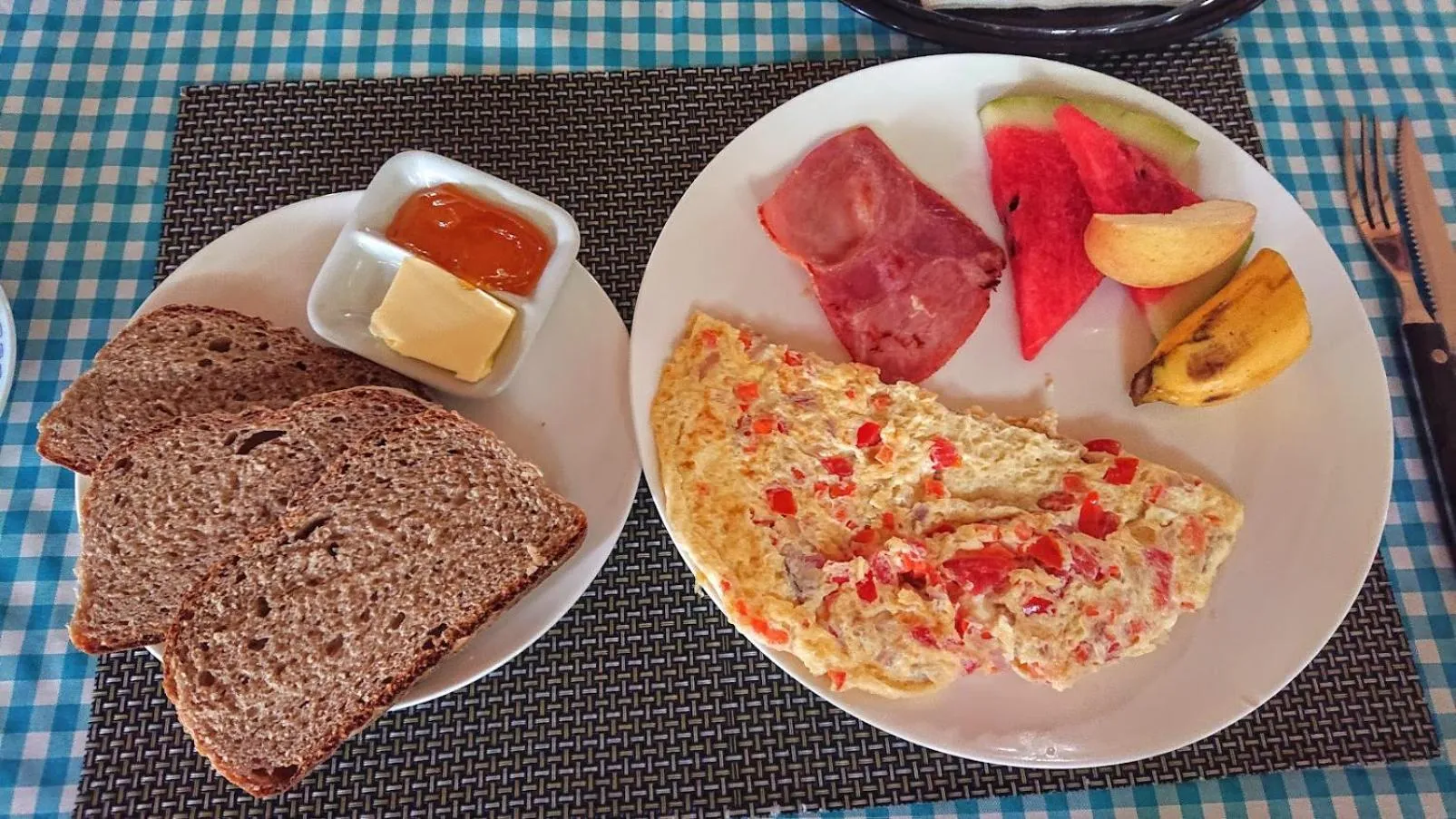 Assiette de petit-déjeuner avec omelette, fruits et pain.