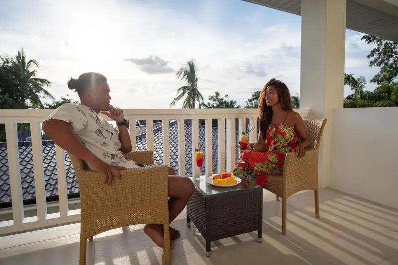 Deux personnes sont assises à une table sur une terrasse ensoleillée.