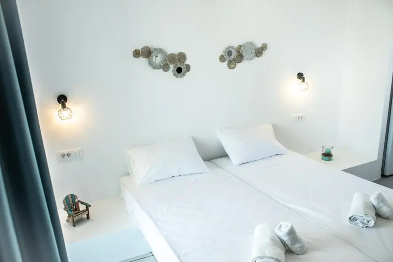 Un lit blanc est fait dans une chambre lumineuse et minimaliste.