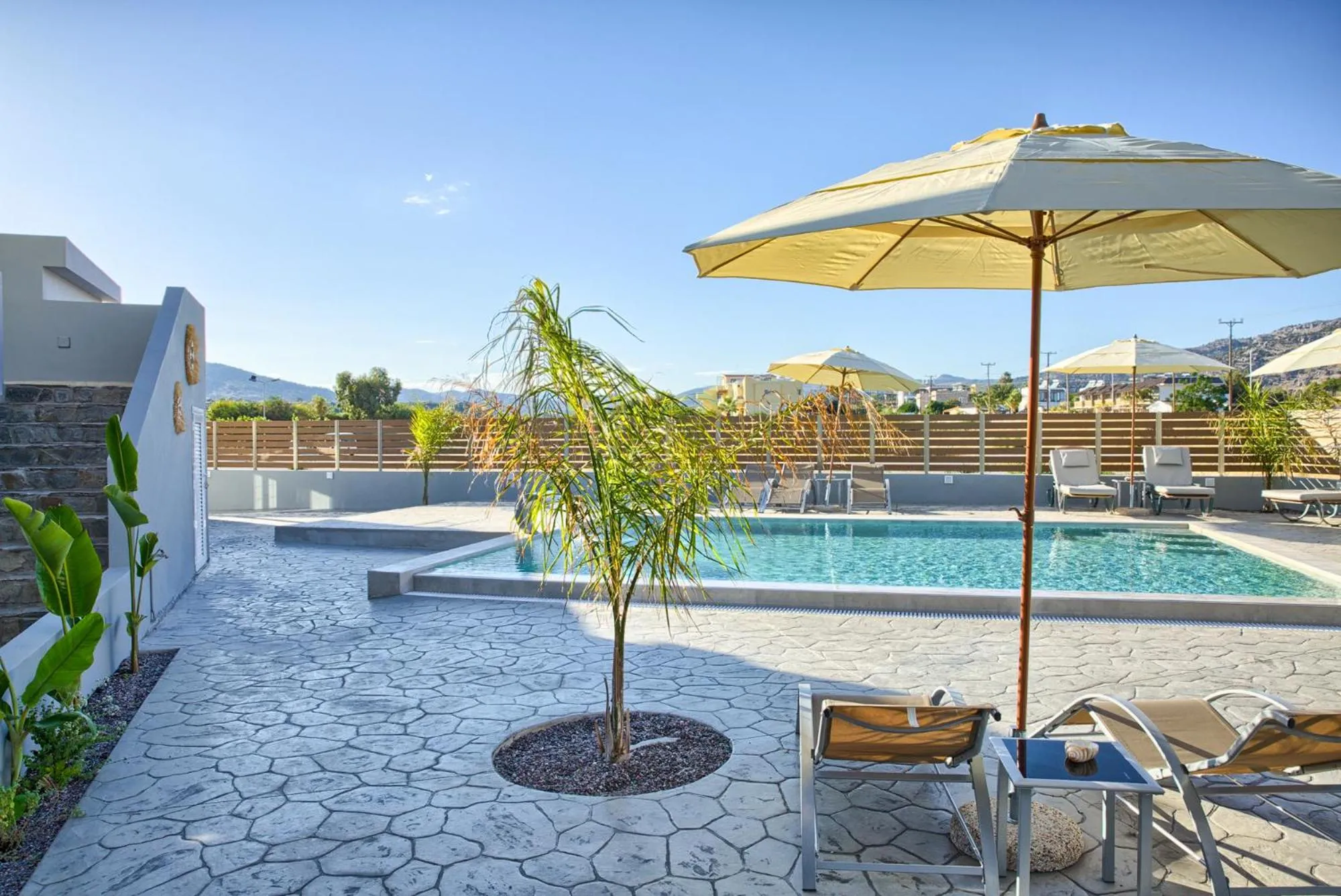 Terrasse avec transats et petite piscine ensoleillée.