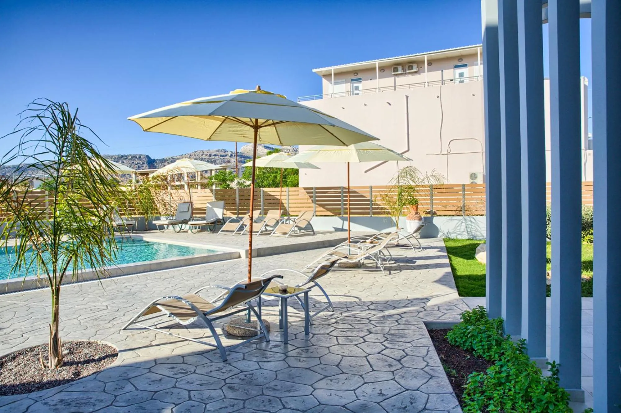 Terrasse avec transats et parasols au bord d'une piscine.