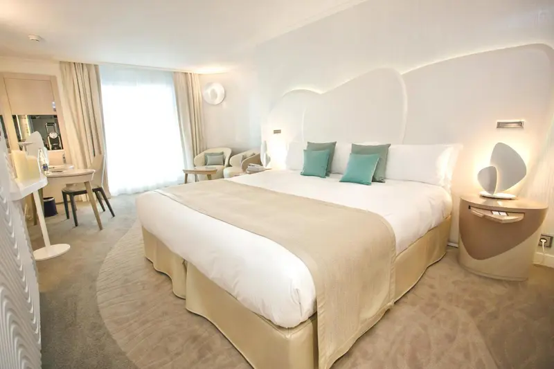Une chambre lumineuse avec un grand lit et un coin salon.
