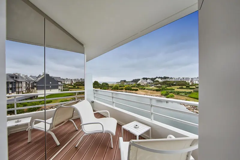 Terrasse aménagée avec mobilier blanc donnant sur un paysage côtier.