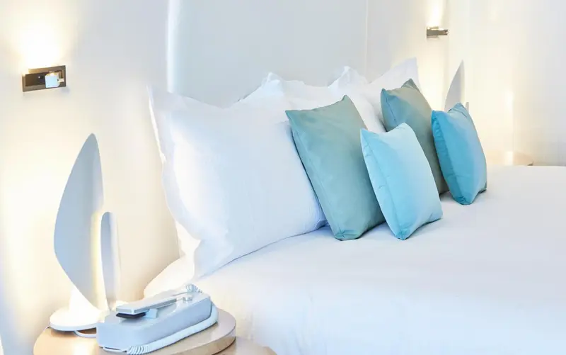 Un lit blanc est garni de plusieurs oreillers et coussins.
