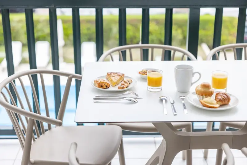 Une table est dressée pour le petit-déjeuner sur une terrasse.