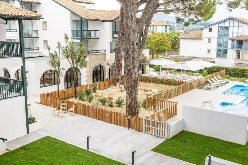 Vue aérienne d'un bâtiment blanc avec des balcons et une cour intérieure aménagée.