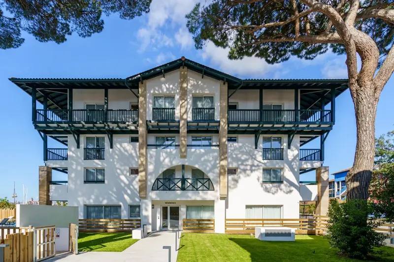 Facade d'un bâtiment blanc à deux étages avec des balcons en bois.