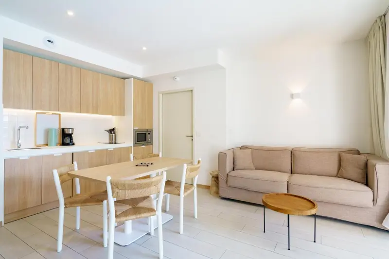 Espace de vie lumineux avec cuisine équipée et coin repas.