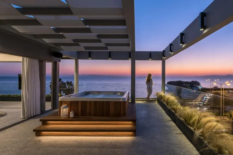 Terrasse avec jacuzzi et vue sur la mer au coucher du soleil.