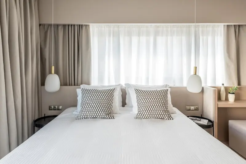 Un lit double est fait dans une chambre lumineuse et minimaliste.