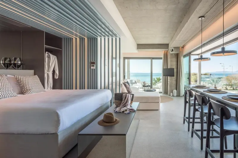 Une chambre moderne avec un grand lit et un espace salon ouvert sur une vue mer.