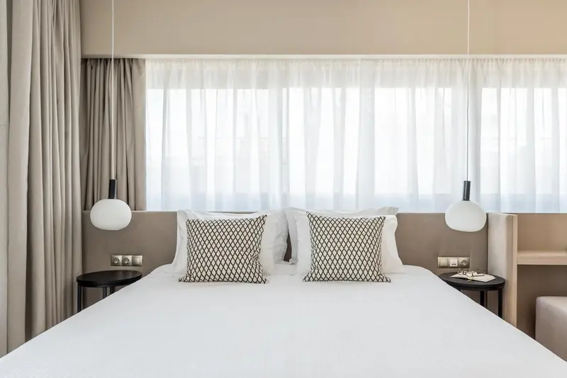 Un lit double avec oreillers décoratifs dans une chambre lumineuse.