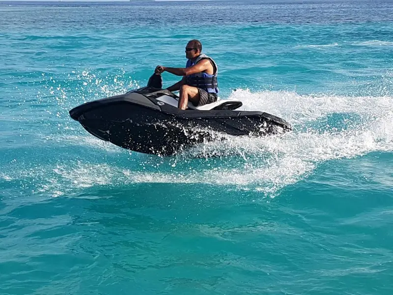 Une personne conduit un jet-ski sur une eau turquoise.
