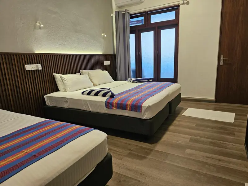 Une chambre avec deux lits simples et un lit double.
