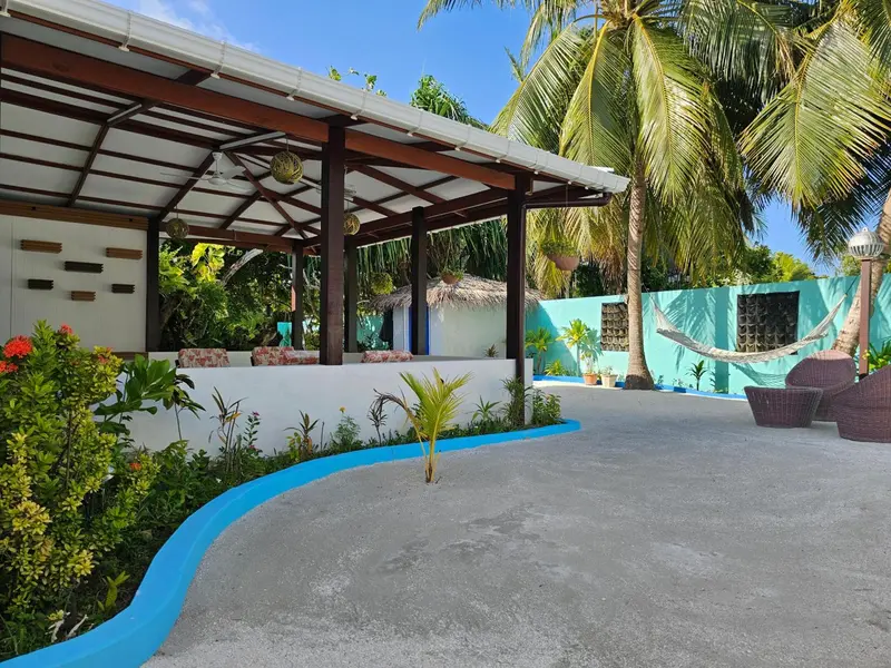 Terrasse ombragée avec mobilier de détente et végétation tropicale.