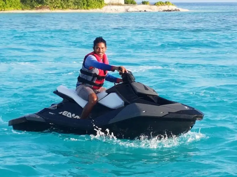 Une personne conduit un jet ski sur une eau turquoise.