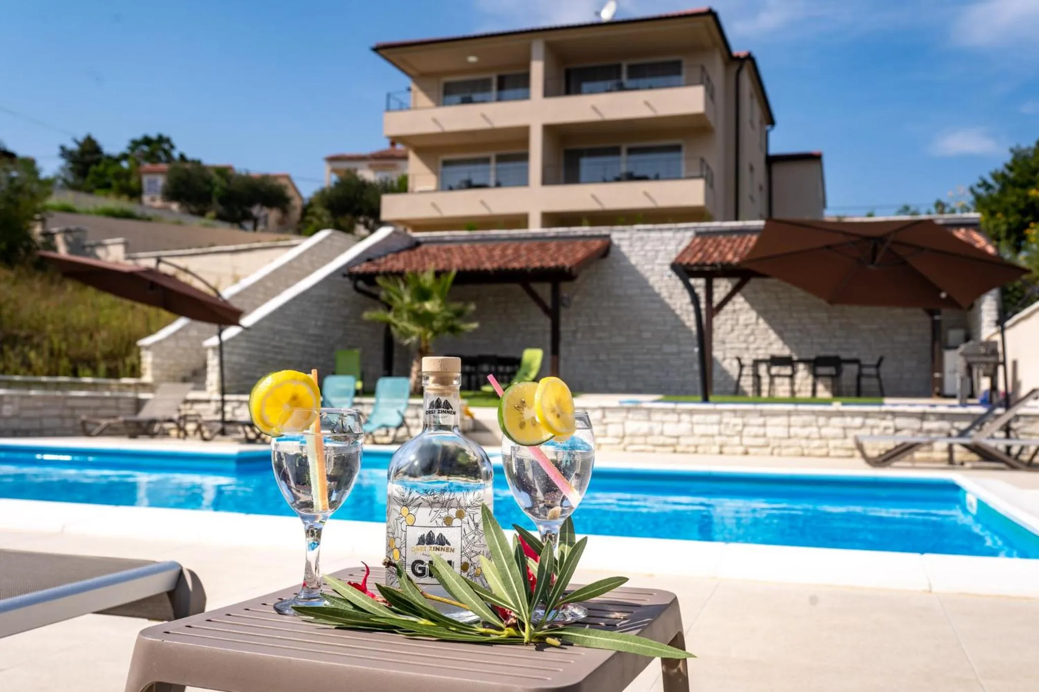 Deux verres de cocktail rafraîchissants sur une table basse au bord d'une piscine ensoleillée.