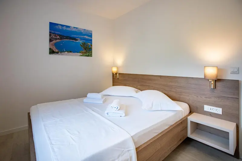 Une chambre lumineuse avec un grand lit recouvert de draps blancs et d'oreillers.
