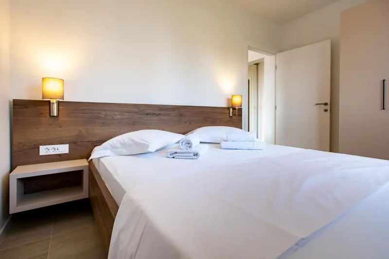 Une chambre lumineuse avec un grand lit blanc et des lampes murales.
