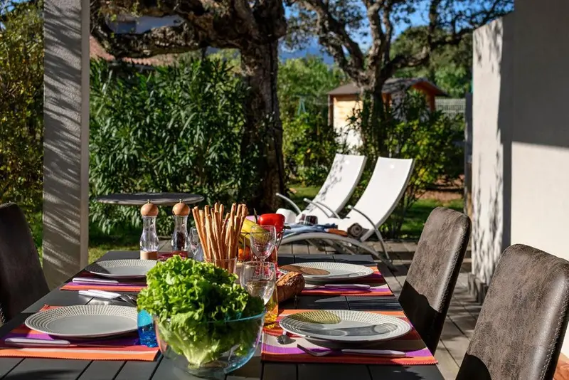 Une table dressée pour un repas en extérieur avec une salade fraîche et des couverts colorés.