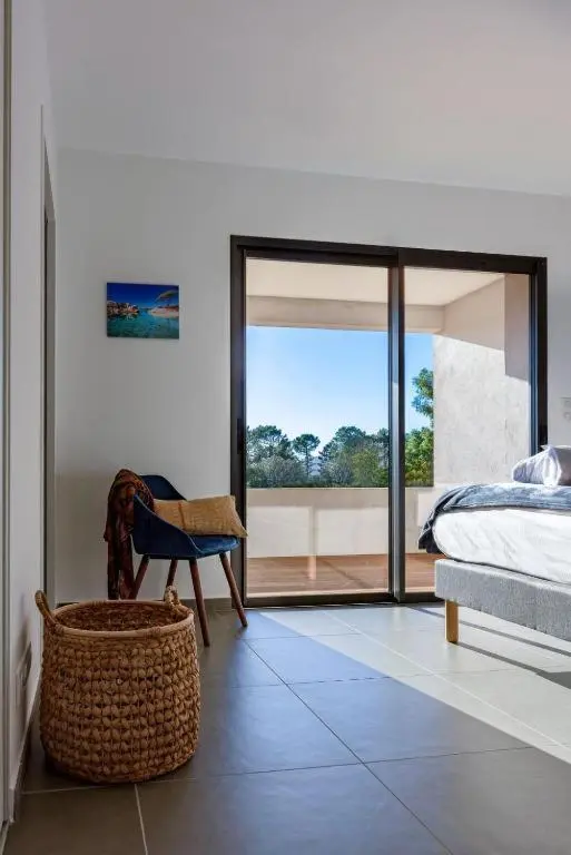 Une chambre lumineuse s'ouvre sur une terrasse avec vue sur la végétation.