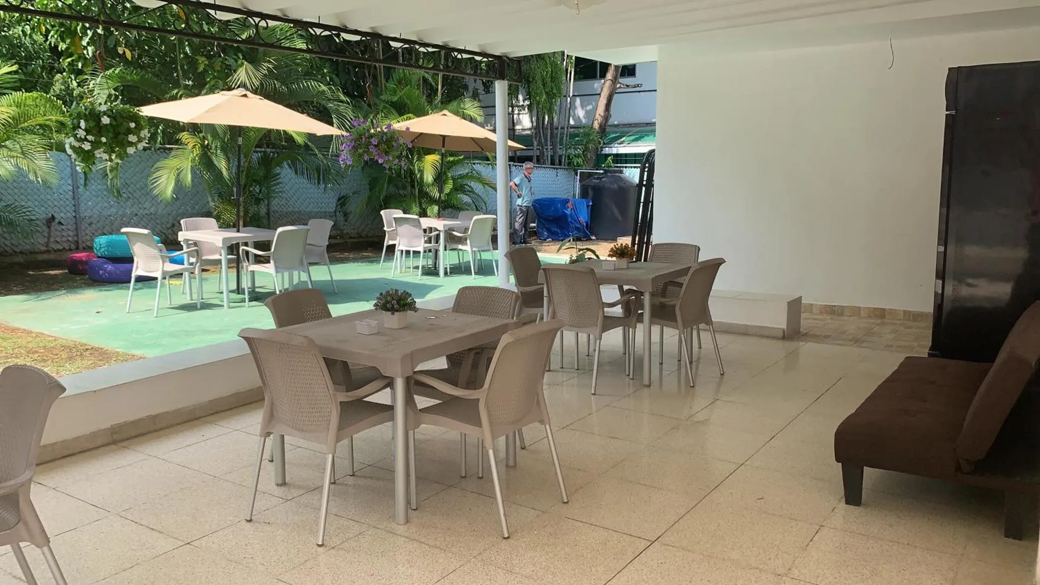 Terrasse ombragée avec tables et chaises en plastique.