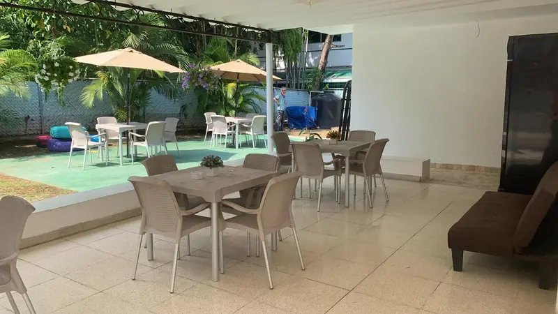 Terrasse ombragée avec tables et chaises en plastique.