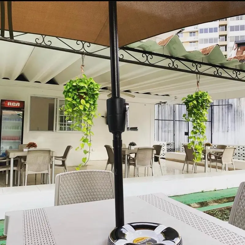 Terrasse ombragée avec tables et chaises en plastique.