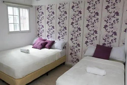 Une chambre avec deux lits simples et un mur décoré de motifs floraux.
